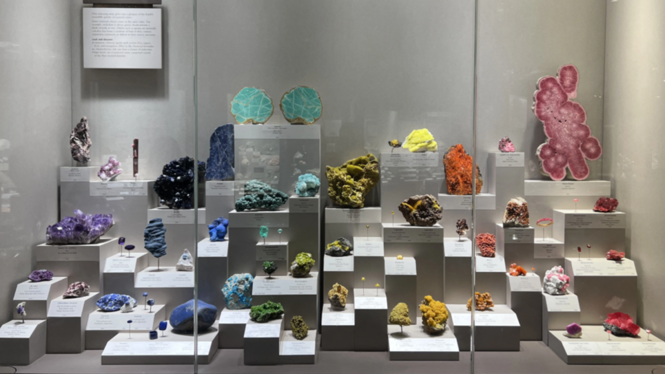 A display of minerals arranged by color to create a rainbow effect.
