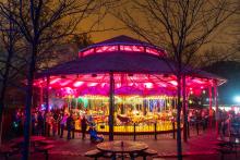 The Speedwell Conservation Carousel is the only paid ticketed attraction open at ZooLights pending weather. The Zoo's carousel is lit up pink and yellow.
