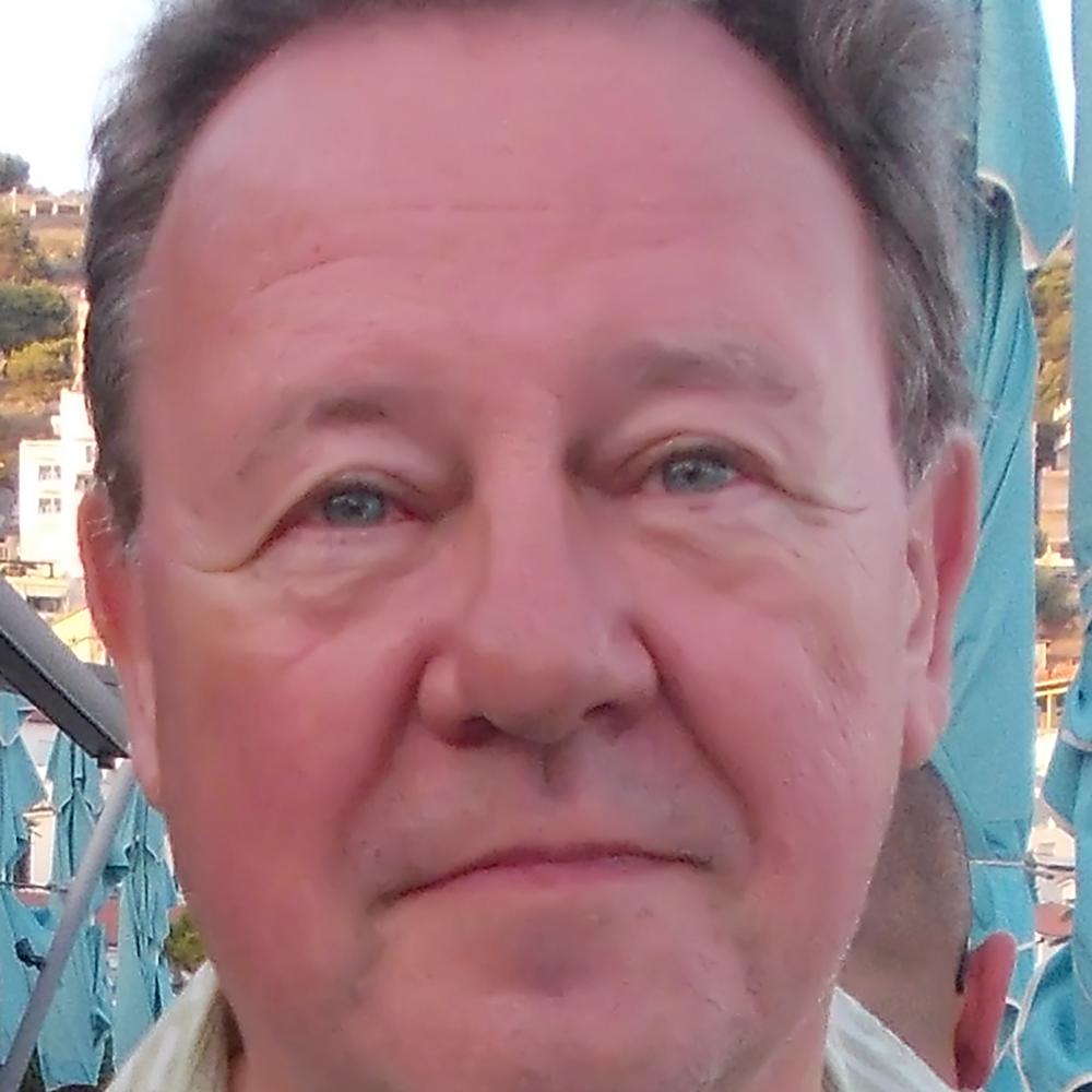 Headshot of a blue-eyed man with curly hair.